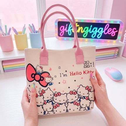 Light-coloured Hello Kitty tote bag with pink handles and bow print, shown open with stationery
