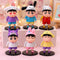 Shinchan figure wearing a white cat bow hat and red outfit, with other character-themed designs behind
