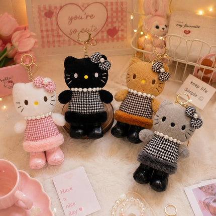 Four Hello Kitty plush bag charms in white, black, brown and grey with bows and patterned outfits