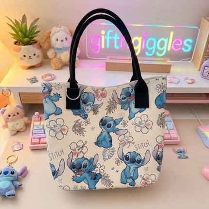 Floral Stitch tote bag with black handles and all-over blue character print, styled with accessories