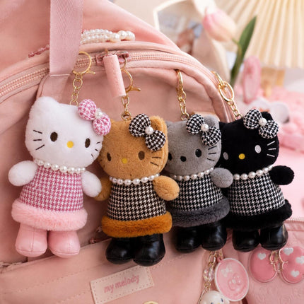 Four Hello Kitty plush bag charms hanging from a pink bag by gold-tone ring chains