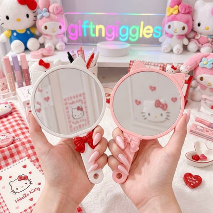 Reflective side of white and pink cat-ear handheld mirrors with bow handles
