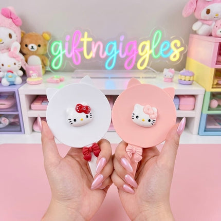 White Hello Kitty-style cat-ear handheld mirror and matching comb with red bows